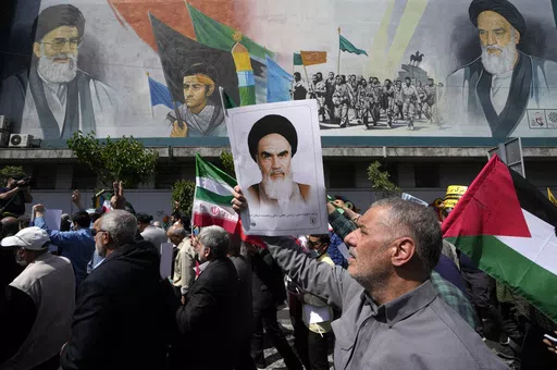 Iranian worshippers walk past a mural showing the late revolutionary founder Ayatollah Khomeini, right, Supreme Leader Ayatollah Ali Khamenei, left, and Basij paramilitary force, as they hold posters of Ayatollah Khomeini and Iranian and Palestinian flags in an anti-Israeli gathering after Friday prayers in Tehran, Iran, April 19, 2024. This month's unprecedented direct attacks between Iran and Israel are revealing deeper insights into both militaries. Experts say Friday's apparent precision str