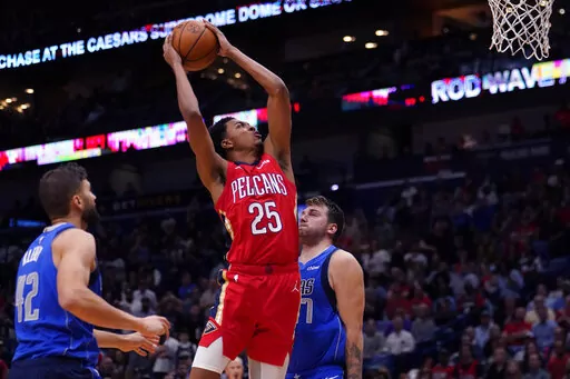 New Orleans Pelicans guard Trey Murphy III (25) goes to the basket between Dallas Mavericks forward Maxi Kleber (42) and guard Luka Doncic (77) in the second half of an NBA basketball game in New Orleans, Tuesday, Oct. 25, 2022. The Pelicans won 113-111. (AP Photo/Gerald Herbert)