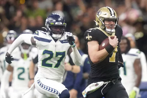 New Orleans Saints' Taysom Hill heads to the end zone for a 60 yard rushing touchdown as Seattle Seahawks' Tariq Woolen pursues during an NFL football game in New Orleans, Sunday, Oct. 9, 2022. (AP Photo/Gerald Herbert)