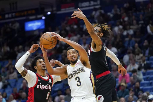 New Orleans Pelicans guard CJ McCollum (3) goes to the basket between Portland Trail Blazers guard Keon Johnson (6) and forward Greg Brown III in the second half of an NBA basketball game in New Orleans, Thursday, April 7, 2022. (AP Photo/Gerald Herbert)